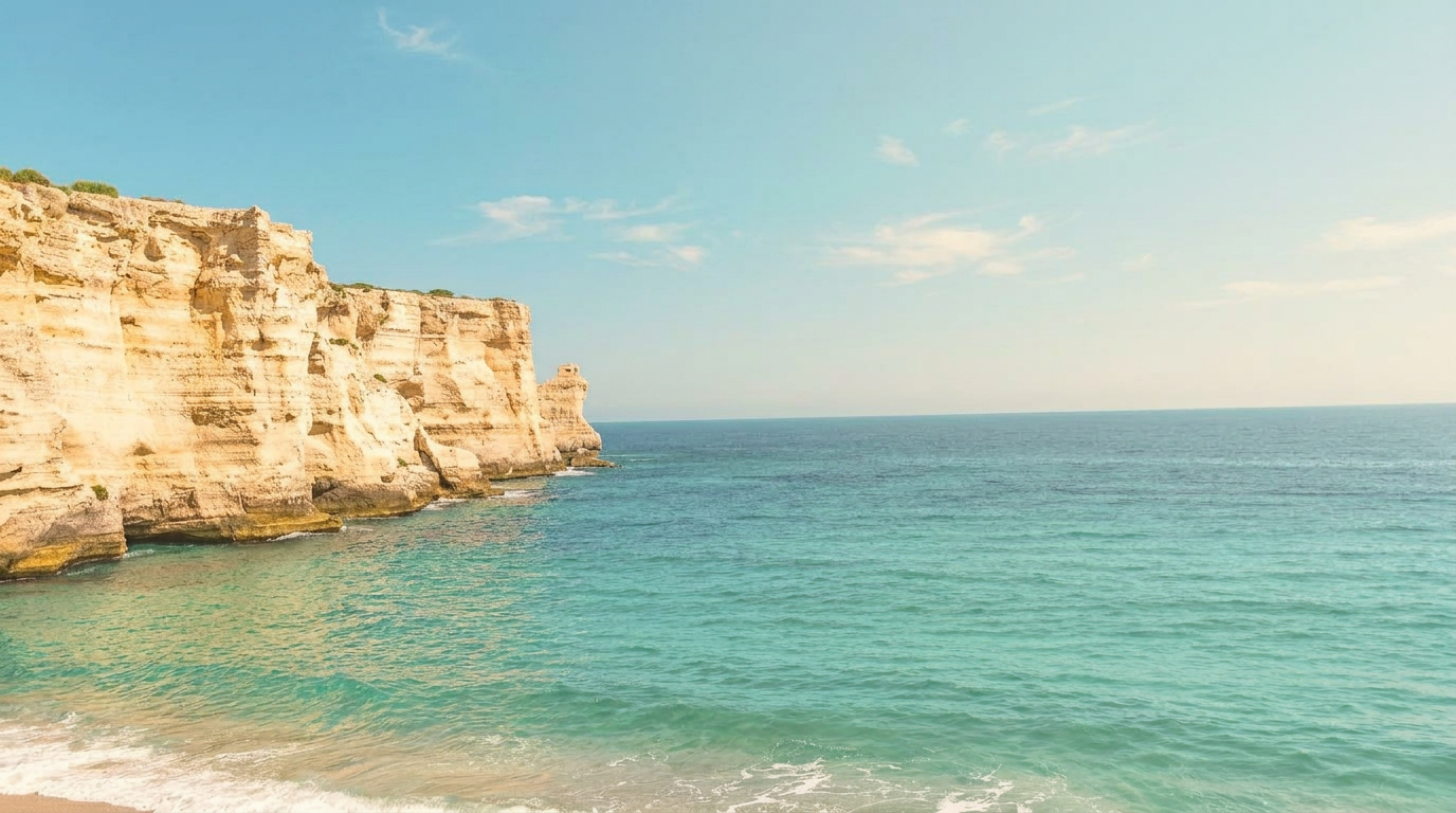 Turquoise Mediterranean cove at golden hour with pale cliffs, olive trees and a stone path leading toward the sea